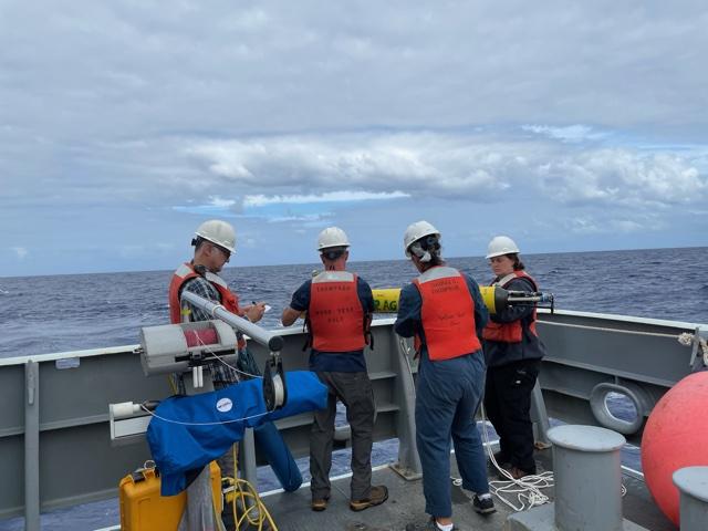 Research ship crew members deploying scientific float in the ocean.