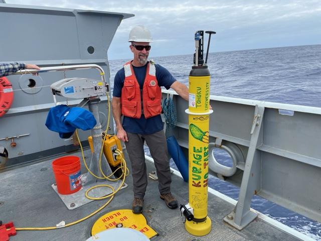 Crewmember displaying research float on deck of research ship in the ocean.